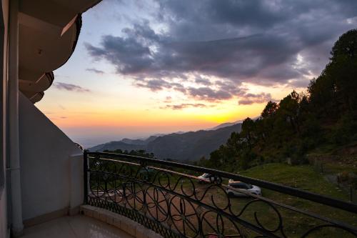 a view of a sunset from a balcony at FabHotel SN Resort in Dharamshala