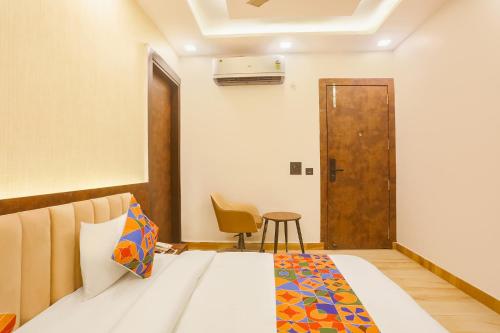 a bedroom with a bed and a chair and a door at FabExpress Sugar Inn Near Rajouri Garden in New Delhi