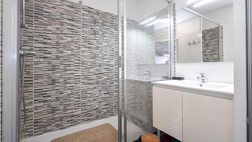 une salle de bain blanche avec une douche et un lavabo dans l'établissement La Dune B N204 - 2P4, à Sérignan