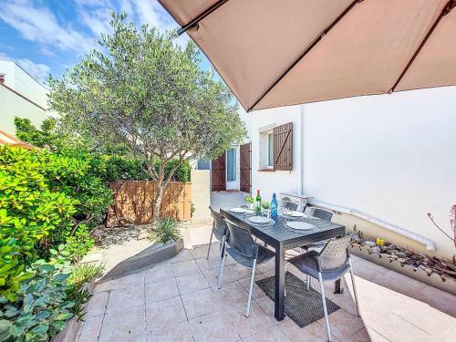 un patio avec une table, des chaises et un parasol dans l'établissement Holiday Home Les Marines-5 by Interhome, au Barcarès