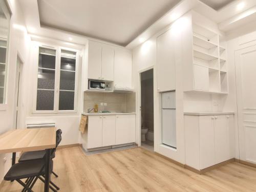 une cuisine avec des armoires blanches et une table en bois dans l'établissement Appartement romantique Tour Eiffel à vos pieds, à Paris