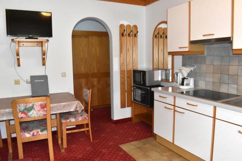 a kitchen with white cabinets and a table with a microwave at Altachhof Hotel und Ferienanlage - Jokercard im Sommer inklusive in Saalbach Hinterglemm