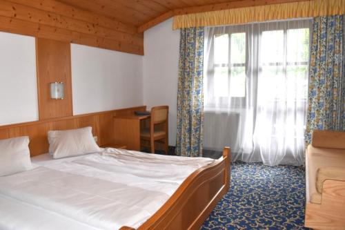 a bedroom with a large bed and a window at Altachhof Hotel und Ferienanlage - Jokercard im Sommer inklusive in Saalbach Hinterglemm