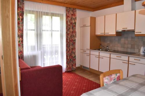 a kitchen with white cabinets and a red carpet at Altachhof Hotel und Ferienanlage - Jokercard im Sommer inklusive in Saalbach Hinterglemm