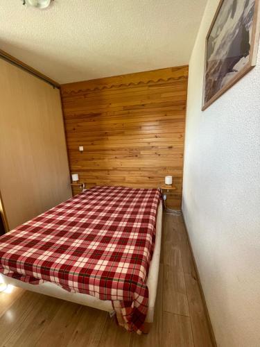 une chambre avec un lit avec une couverture à carreaux dans l'établissement La Foux d'Allos, à Allos