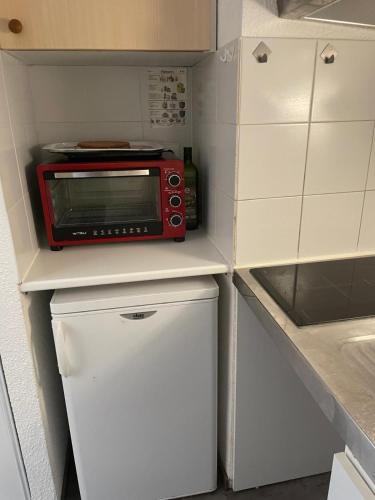 une petite cuisine avec un micro-ondes rouge au-dessus d'un réfrigérateur dans l'établissement La Foux d'Allos, à Allos