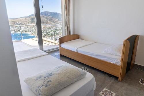 two beds in a room with a large window at Stunning Sea View Cosy Apartment in Gundogan