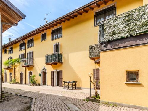 a yellow building with a table on a cobblestone street at Apartment Tre Laghi by Interhome in Carlazzo
