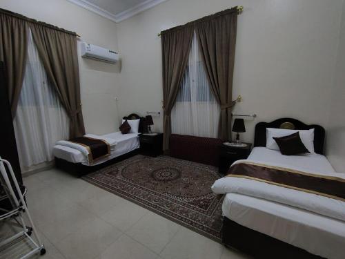 a hotel room with two beds and a rug at العييري للشقق المخدومة النعيرية 1 in Al Nairyah