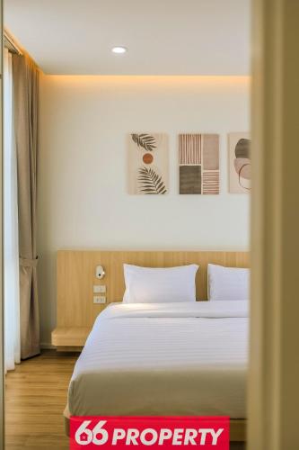 a bedroom with a white bed and some pictures on the wall at Modern 4 BR Home - Walk to Shopping and Supermarket in Chiang Mai