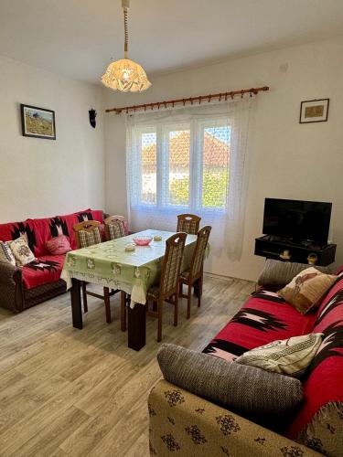 a living room with a table and a couch at Idila pod Rtnjem - Najam cele vikendice sa bazenom in Ilino