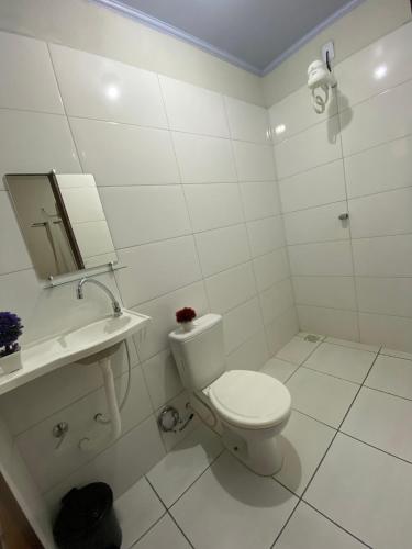 a white bathroom with a toilet and a sink at Pousada Dona Dulce in Barreirinhas