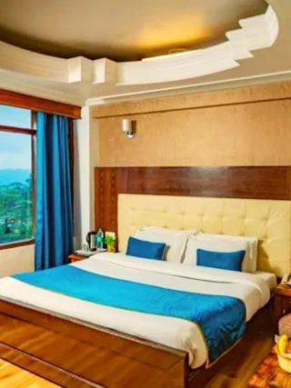 ein Schlafzimmer mit einem großen Bett mit blauen Kissen in der Unterkunft Alarks Inn in Shimla
