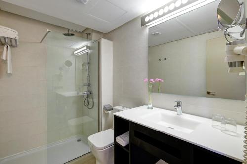 a bathroom with a sink and a toilet and a mirror at Hipotels Mediterraneo Club in Sa Coma