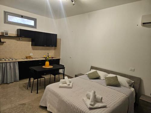 a bedroom with a bed and a kitchen with a table at Casa vacanze Poma in Custonaci