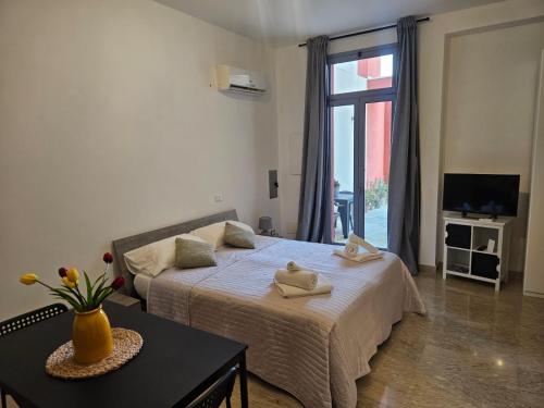 a bedroom with two beds and a tv and a window at Casa vacanze Poma in Custonaci