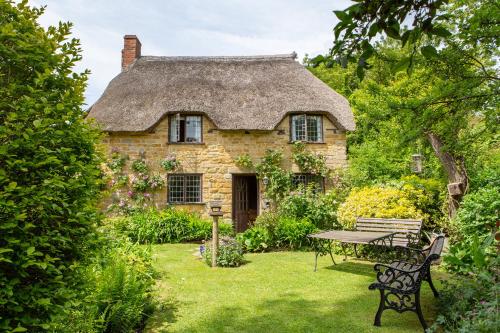 an old stone house with a thatched roof and a picnic table at Strongate Cottage Rural Retreat - near Bridport & Jurassic Coastline in Netherbury
