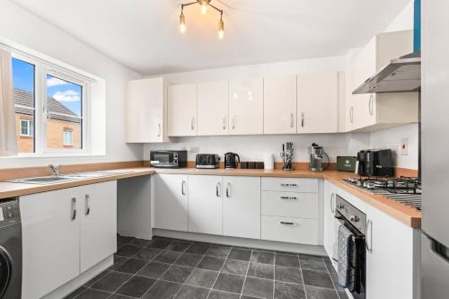 a white kitchen with white cabinets and a sink at Spacious 3-Bed Home, Parking, Garden, Sleeps 7 in Brettell Lane