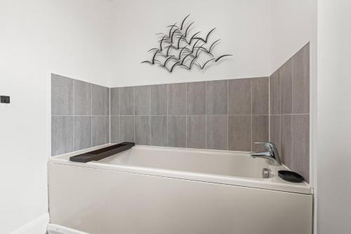 a bathroom with a bath tub with a plant on the wall at Spacious 3-Bed Home, Parking, Garden, Sleeps 7 in Brettell Lane