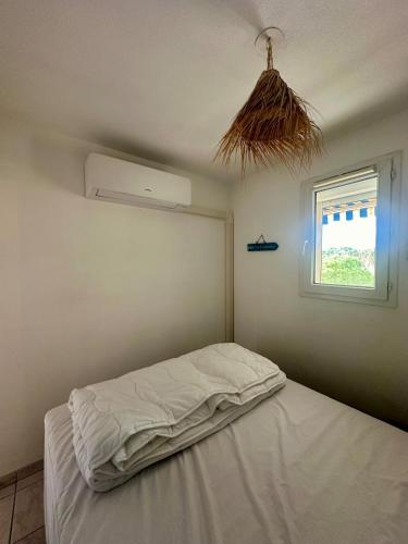 un lit blanc dans une chambre avec une fenêtre dans l'établissement Cozy T2 avec piscine Le Lavandou, au Lavandou
