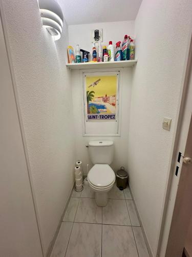 une salle de bain avec des toilettes avec une étagère au-dessus dans l'établissement Cozy T2 avec piscine Le Lavandou, au Lavandou
