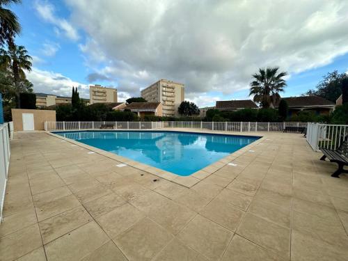 - une piscine avec banc à côté d'un bâtiment dans l'établissement Cozy T2 avec piscine Le Lavandou, au Lavandou