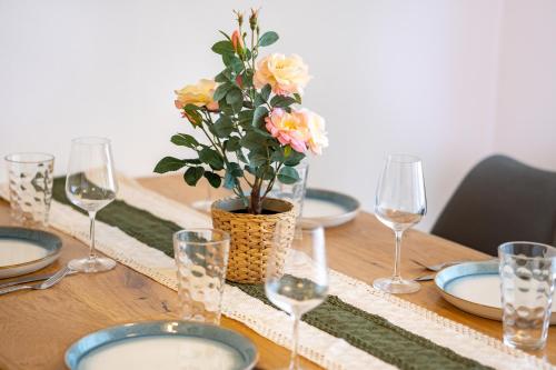 a wooden table with glasses and a vase with flowers at Design Apartment Bavaria - Küche, Smart-TV & Mehr in Scheyern