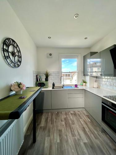 a kitchen with white cabinets and a large clock on the wall at Seaside Apartment close to beach, town, station in Broadstairs