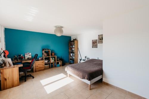 - une chambre avec un mur bleu, un lit et un bureau dans l'établissement Villa au calme avec piscine, à Saint-Jean-Pla-de-Corts