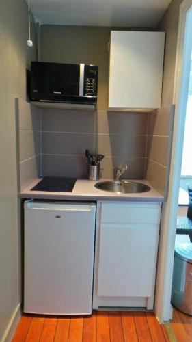 une petite cuisine avec un évier et un micro-ondes dans l'établissement Studio, 128 Rue Jean Jaurès, à La Celle-sous-Gouzon