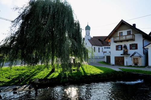 a tree in front of a house and a river at Ferienwohnung Landliebe in Dießen am Ammersee