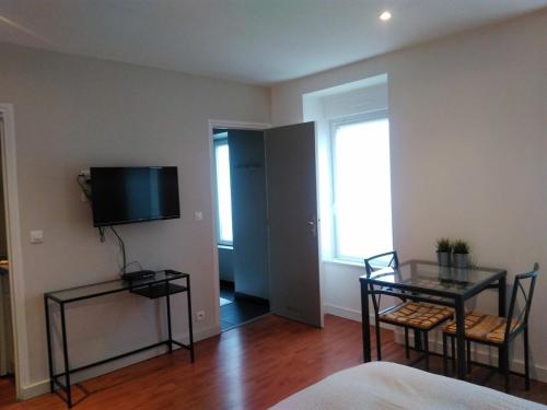 un salon avec une table et une télévision au mur dans l'établissement Studio, 128 Rue Jean Jaurès, à La Celle-sous-Gouzon