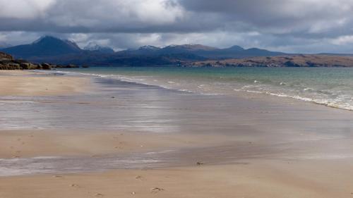 a beach with the ocean and mountains in the background at Little Haven in Gairloch