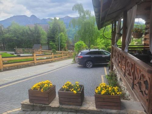 a car parked next to a building with flowers on the street at Apartament Kalina-Mocarni in Kościelisko