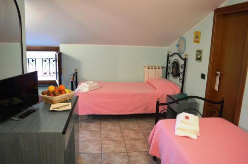 a room with two beds with pink sheets and a television at Antiche Terre Hotel & Relax in Pignone