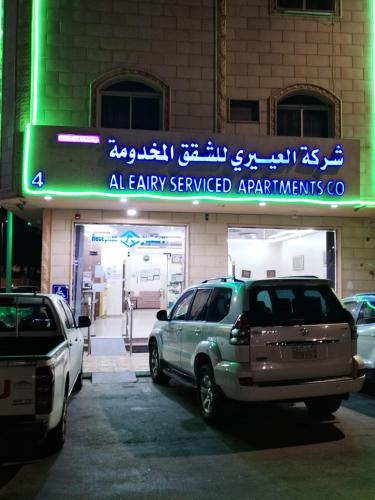 a parking lot with cars parked in front of a building at العييري للشقق المفروشة حائل 4 in Hail
