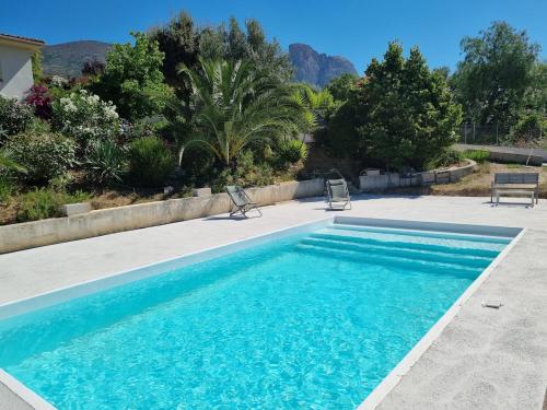 une piscine avec deux chaises à côté d'une maison dans l'établissement T2, rez de villa avec piscine, à Afa