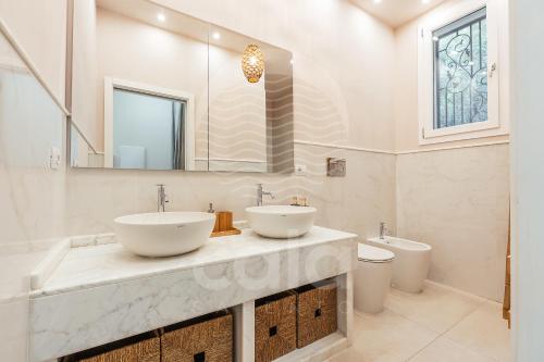 a bathroom with two sinks and a toilet at Dimora Tesoro - by Cala Salento in Torre Lapillo