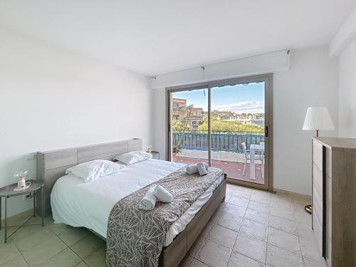 une chambre avec un lit et une grande fenêtre dans l'établissement La pinede Apartement equiped with air conditioning and a pool!, à Antibes