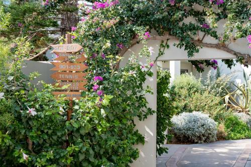 a directional sign in a garden with flowers at Agapi Beach Resort Premium All Inclusive in Amoudara Herakliou