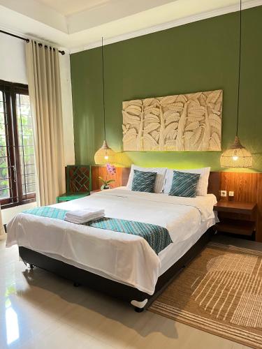 a bedroom with a large bed with a green wall at Villa Padi Cangkringan in Sleman