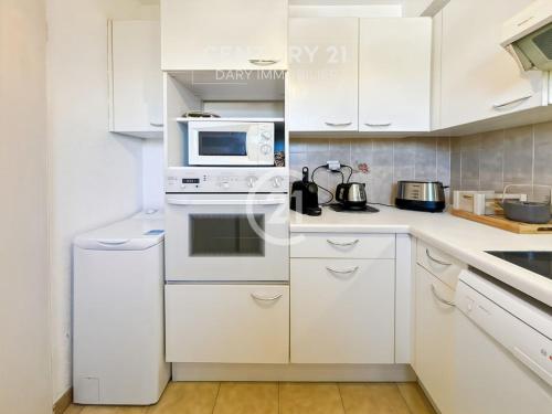 La cuisine est équipée de placards blancs et d'un four micro-ondes. dans l'établissement La Roseraie Calvi, bord de mer, à Calvi