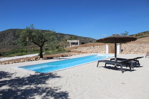 Hondón de las NievesにあるDisfrutaの傘とピクニックテーブルと傘のあるプール