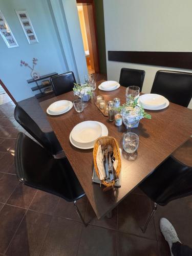 a wooden table with plates and glasses and a basket at Anna Apartment Timișoara in Timişoara