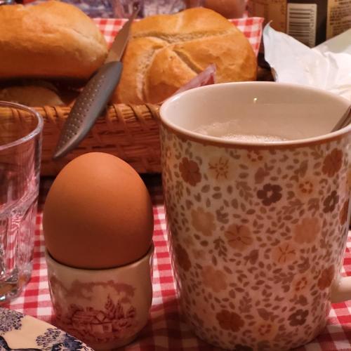 a cup of coffee and an egg next to a basket of bread at Sachserhof Ferienwohnungen in Sachsenburg in Sachsenburg