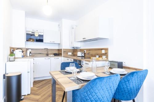 une cuisine avec une table en bois et des chaises bleues dans l'établissement OIQIA • Armoria, à Quimper