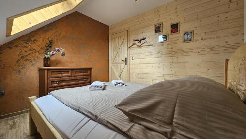 a bedroom with a bed and a wooden wall at Apartament Jaskier in Zakopane