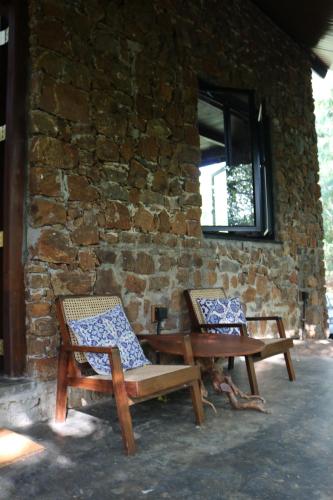 two chairs and a table in front of a brick wall at Passion Hills in Udawalawe