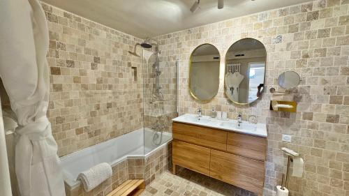 bagno con vasca, lavandino e specchio di Maison Coup de Cœur a Beaune