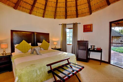 a bedroom with a bed and a bench in a room at Royal Morubisi Founder's Lodge in Kaingo Private Game Reserve